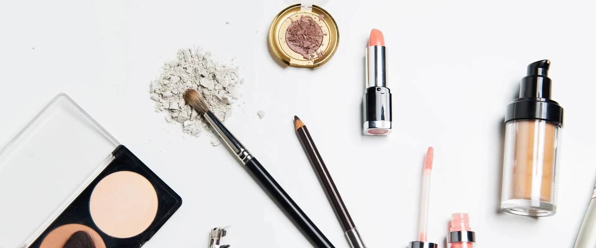 A table topped with makeup and brushes next to some powder.