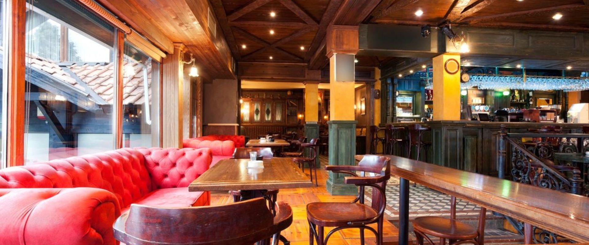 A restaurant with wooden floors and red chairs.